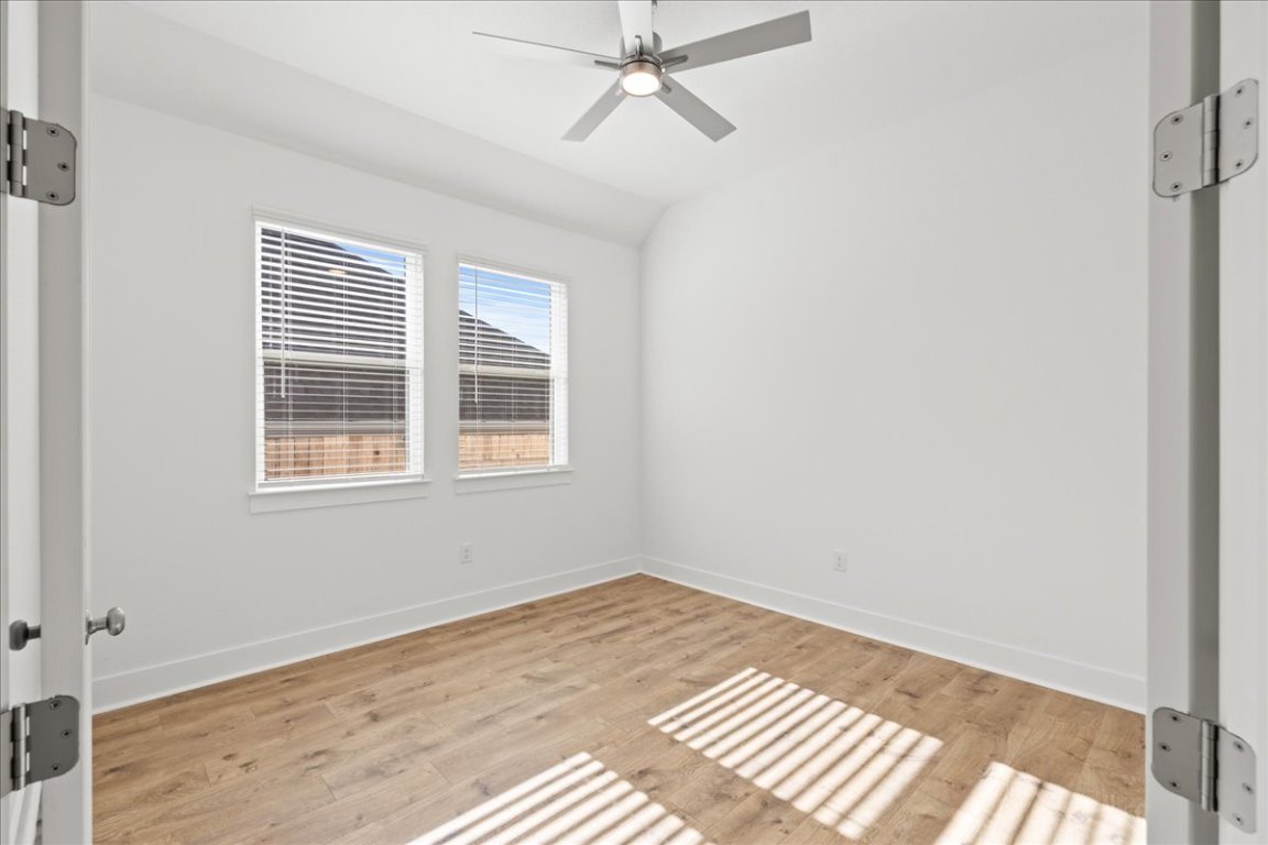 220 Begonia Street Buda, TX 78610 - Photo 11 of 24 a view of an empty room with wooden floor and a window