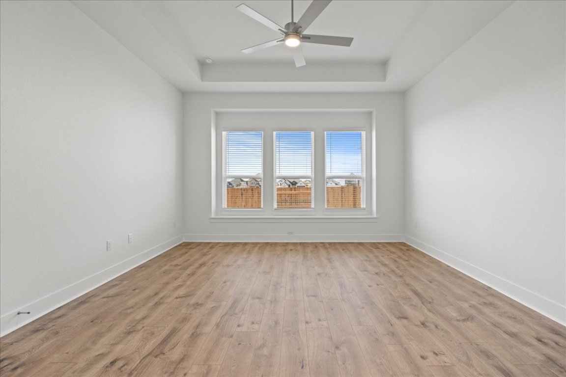 220 Begonia Street Buda, TX 78610 - Photo 12 of 24 an empty room with wooden floor chandelier fan and windows