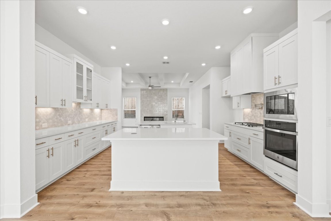 220 Begonia Street Buda, TX 78610 - Photo 9 of 24 a large white kitchen with kitchen island a sink a stove and a refrigerator
