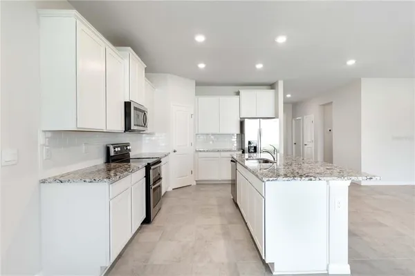 a large kitchen with stainless steel appliances granite countertop a sink and cabinets