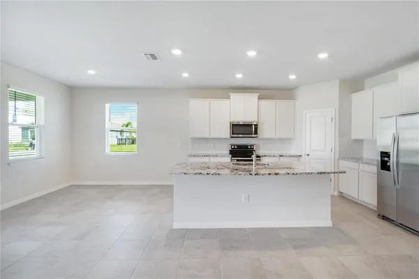 a large kitchen with stainless steel appliances lots of counter top space and a window