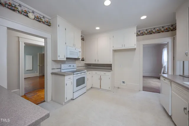 a kitchen with granite countertop white cabinets and white appliances