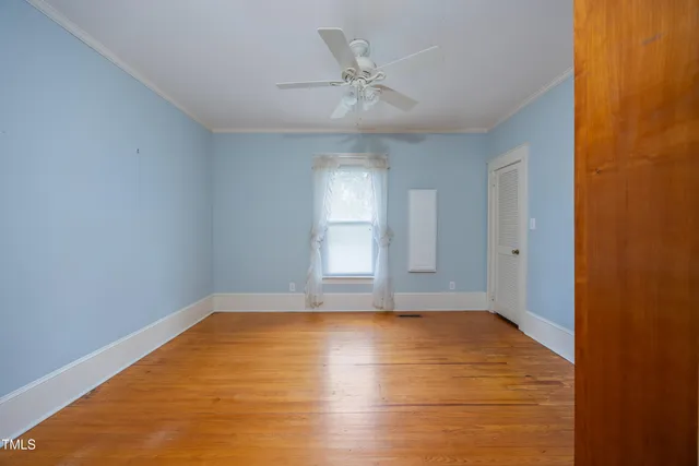 a view of empty room with wooden floor and fan
