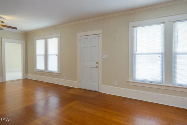 a view of an empty room with wooden floor and a window
