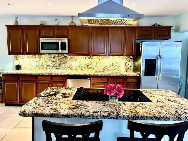 a kitchen with stainless steel appliances kitchen island granite countertop wooden cabinets and a counter top space