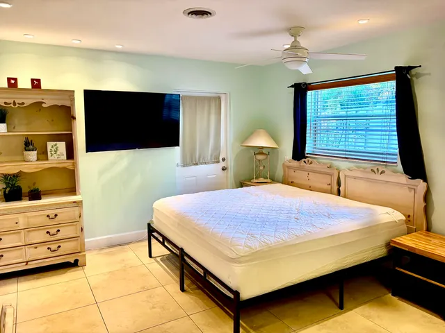 a bedroom with a bed and a flat tv screen on dresser