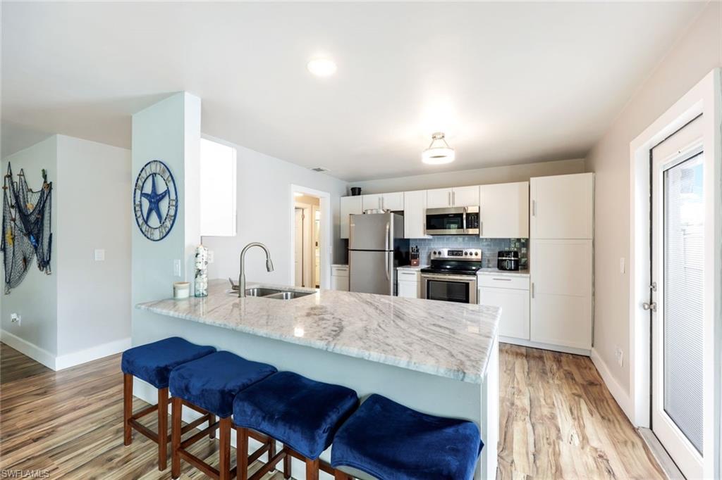 645 101st Avenue North Naples, FL 34108 - Photo 5 of 24 a kitchen with stainless steel appliances granite countertop a stove top oven a refrigerator a sink and dishwasher with wooden floor