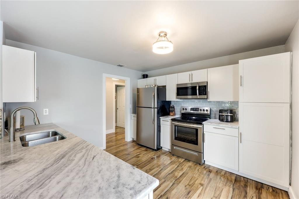 645 101st Avenue North Naples, FL 34108 - Photo 7 of 24 a kitchen with stainless steel appliances granite countertop a sink and a refrigerator