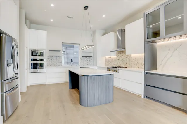 a kitchen with kitchen island a counter top space a sink stainless steel appliances and cabinets