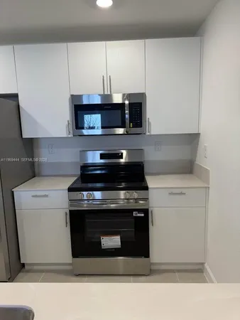 a kitchen with stainless steel appliances granite countertop a stove a microwave and white cabinets
