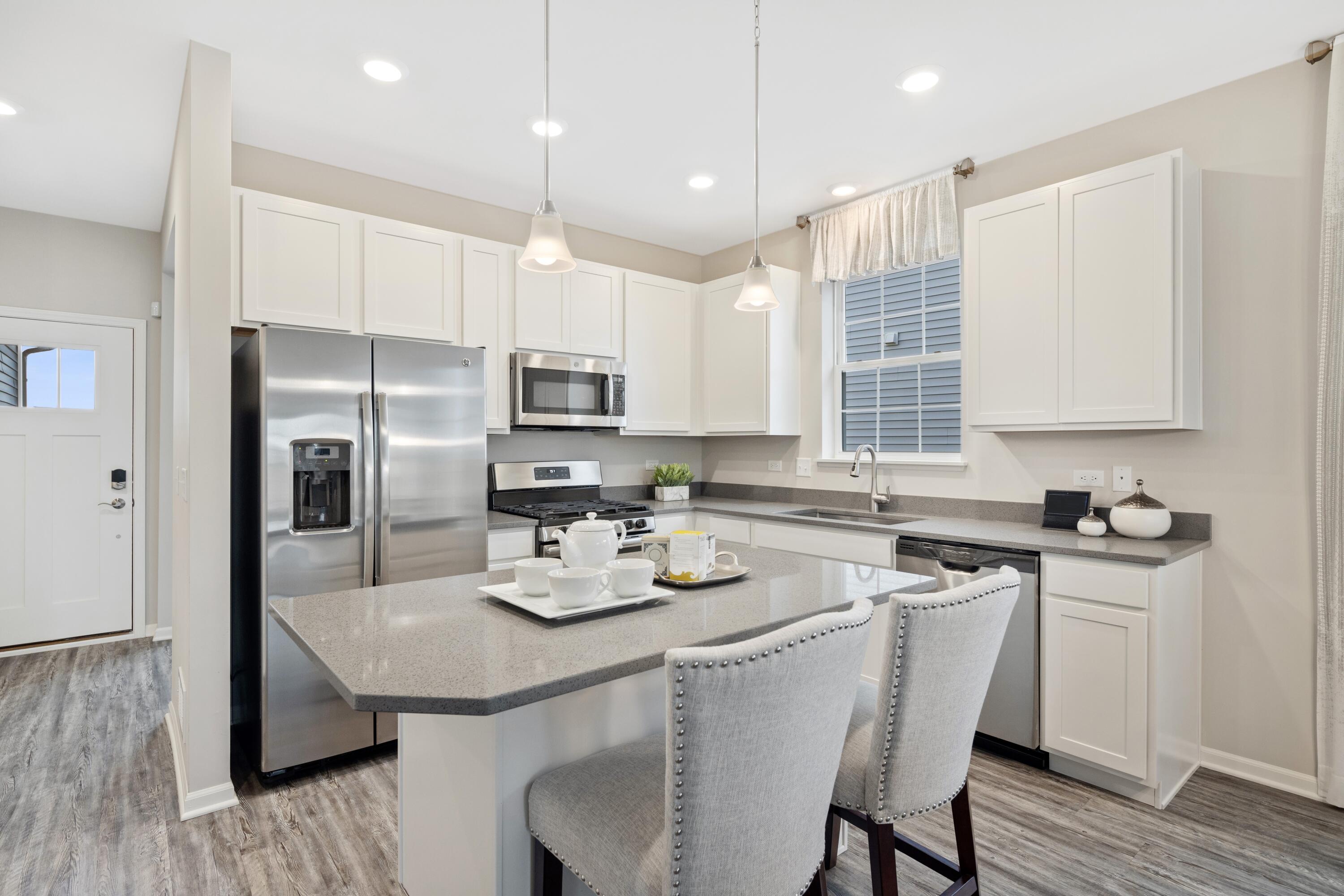 8468 Graystone Drive Lowell, IN 46356 - Photo 7 of 14 a kitchen with a sink a stove a refrigerator and white cabinets with wooden floor