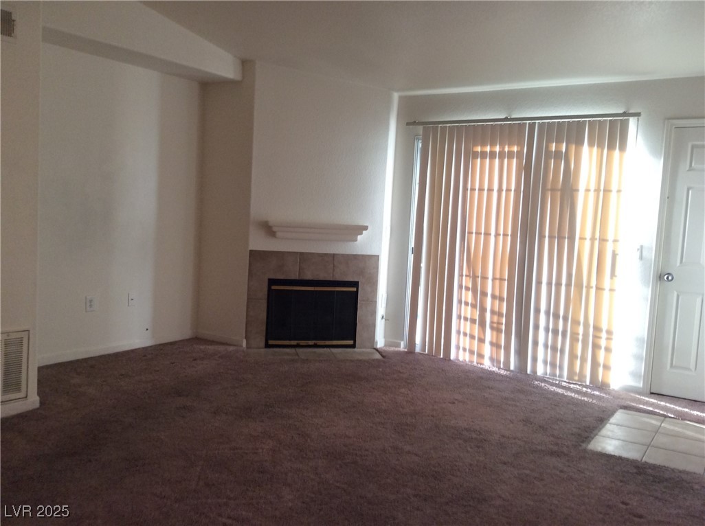 3318 North Decatur Boulevard, Unit 2077 Las Vegas, NV 89130 - Photo 11 of 19 Unfurnished living room featuring carpet, a tiled fireplace, and plenty of natural light