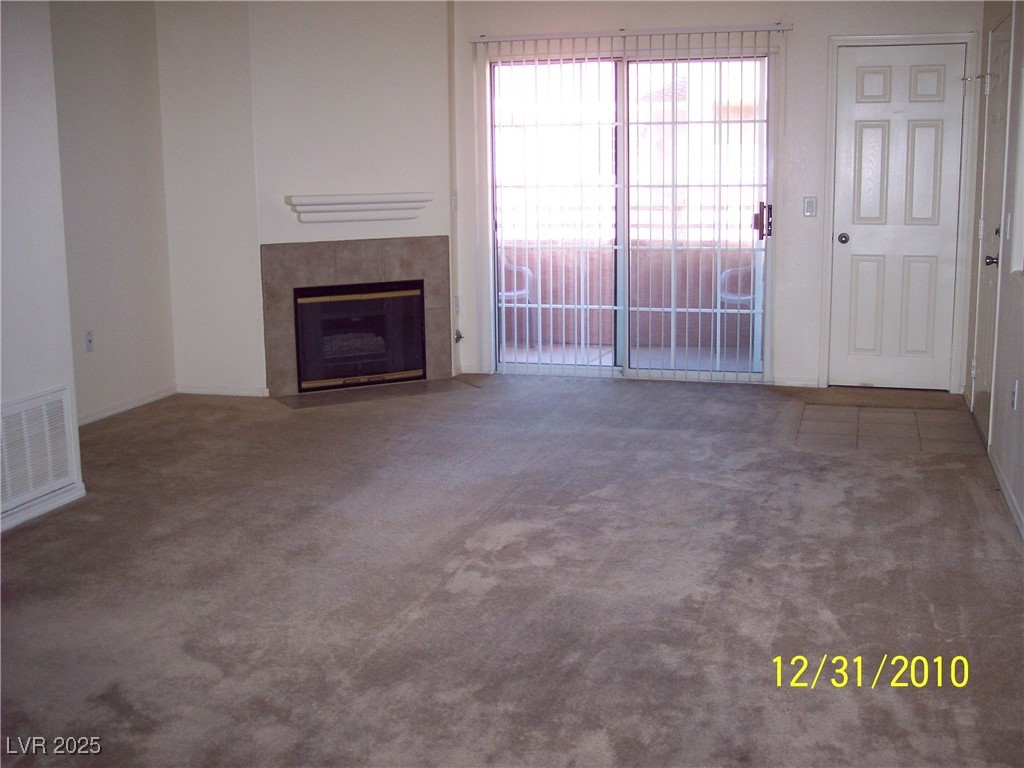 3318 North Decatur Boulevard, Unit 2077 Las Vegas, NV 89130 - Photo 8 of 19 Unfurnished living room featuring carpet flooring and a fireplace