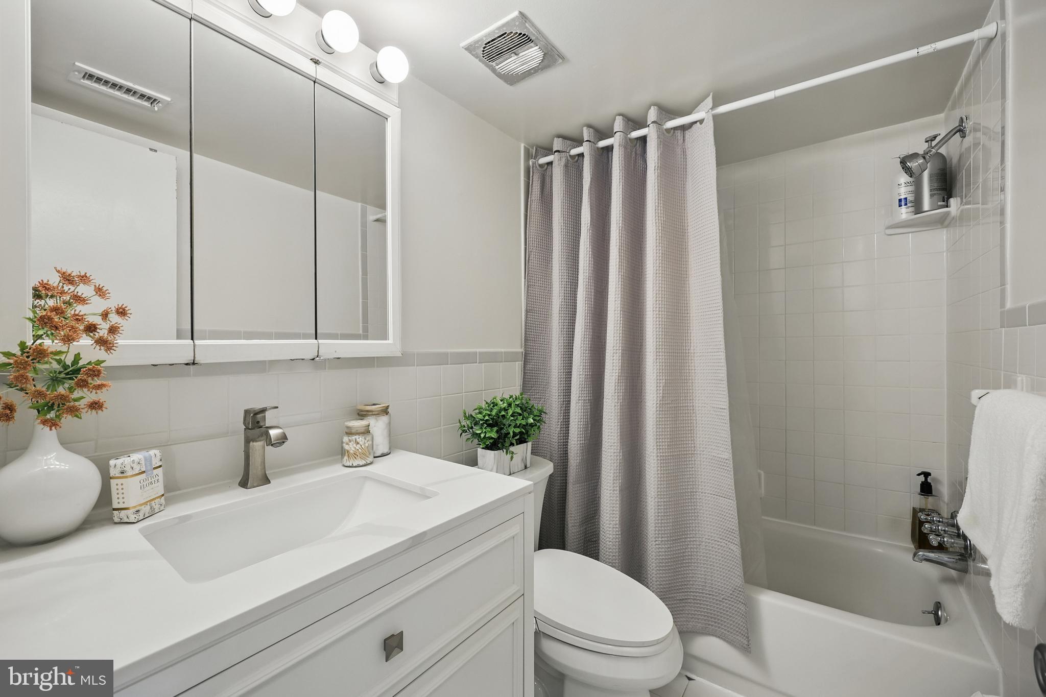 2107 Walsh View Terrace, Unit 14301 & 304 Silver Spring, MD 20902 - Photo 20 of 54 a bathroom with a sink a toilet and shower curtain