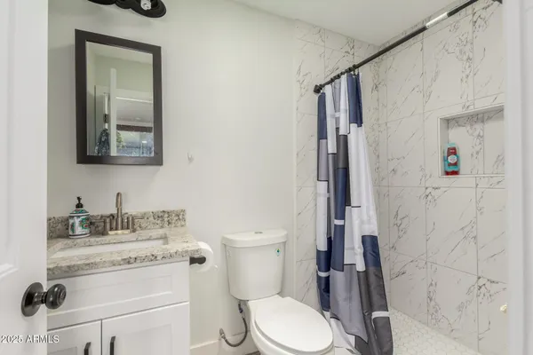 a bathroom with a granite countertop toilet sink and mirror
