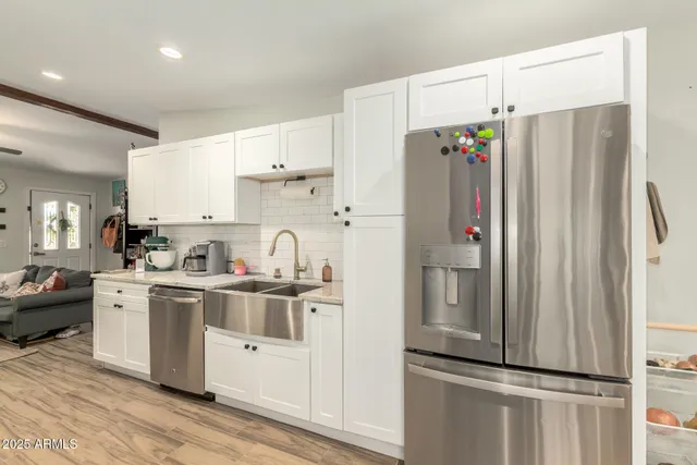 a kitchen with stainless steel appliances a refrigerator a sink and white cabinets