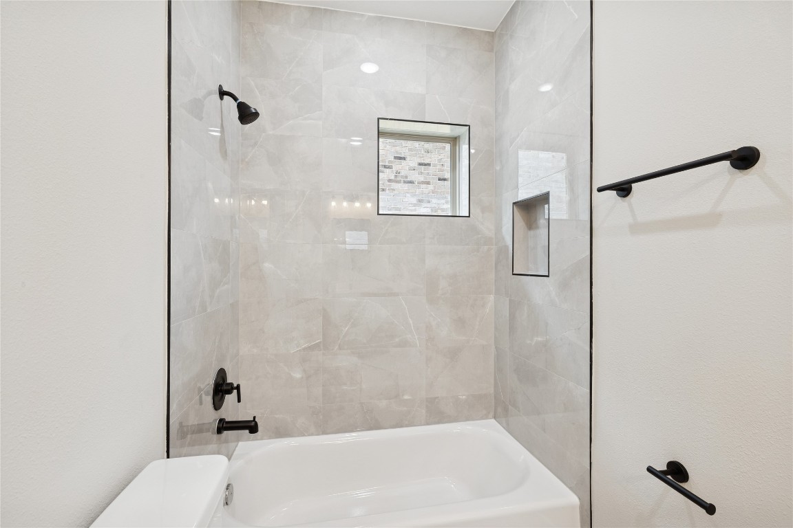 2614 Liguria Lane Spring, TX 77388 - Photo 14 of 23 Elegant secondary bathroom featuring sleek tiles, modern fixtures, and a stylish window for natural light. Perfect for guests or family use.