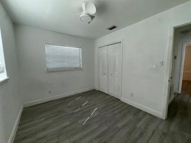 an empty room with wooden floor and windows