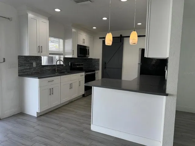 a large kitchen with stainless steel appliances a large counter top a stove a sink a refrigerator and a microwave