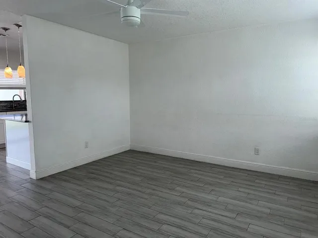 a view of an empty room with wooden floor and a fireplace