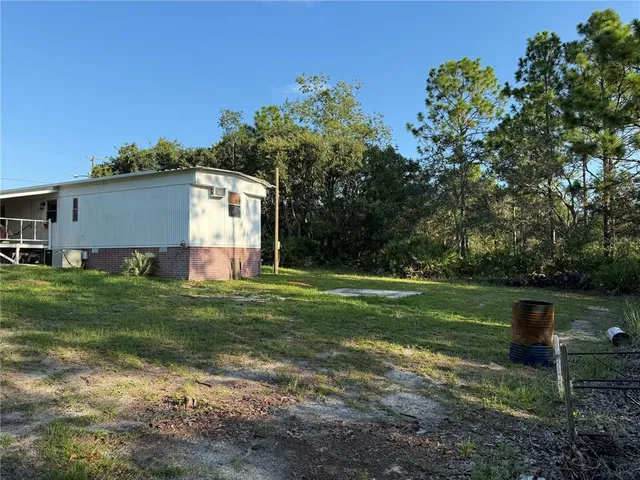 a view of a backyard with table and chairs plants and large tree
