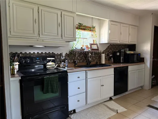 a kitchen with white cabinets and black appliances