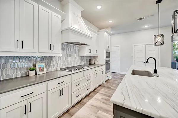 a kitchen with stainless steel appliances kitchen island granite countertop a wooden floor and white cabinets