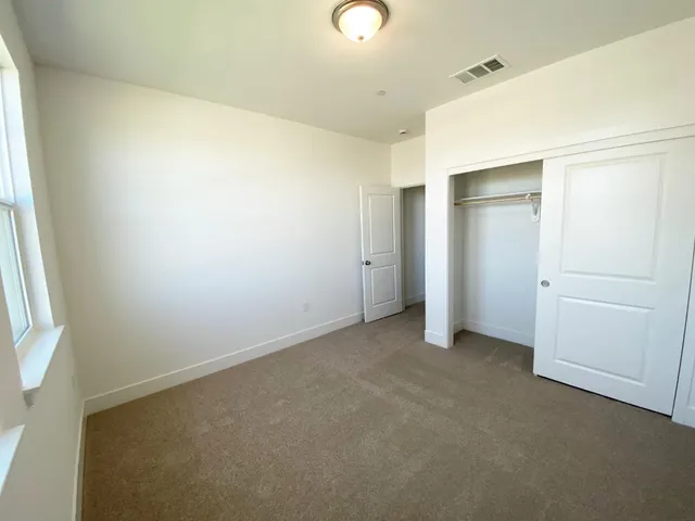 an empty room with closet and windows