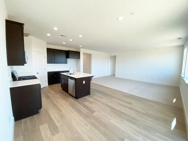 a large kitchen with stainless steel appliances a large counter top a stove and a sink