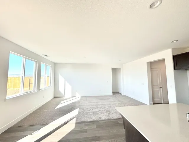 a view of an empty room with window and wooden floor