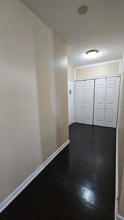 an empty room with wooden floor and fan
