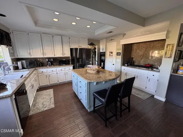 a kitchen with stainless steel appliances granite countertop a stove top oven a sink dishwasher a dining table and chairs with wooden floor