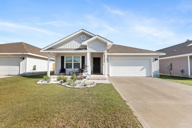 a front view of house with outdoor seating and yard in front of it