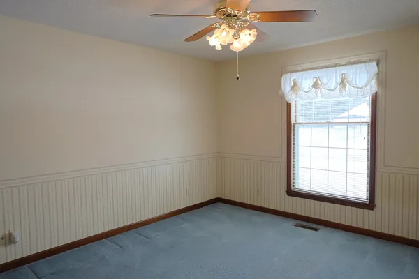 an empty room with windows and fan