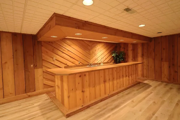 a view of an empty room with wooden floor and a kitchen