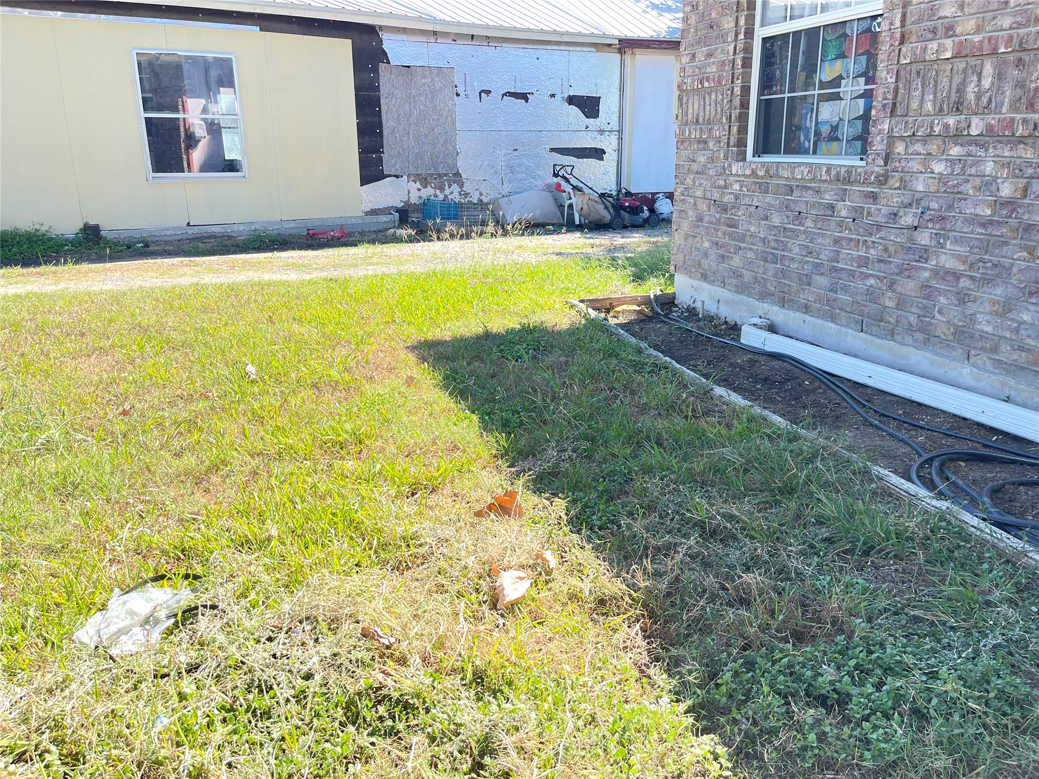 12212 Ballerstedt Road Elgin, TX 78621 - Photo 5 of 29 Brick siding accents this grassy outdoor area located between structures.