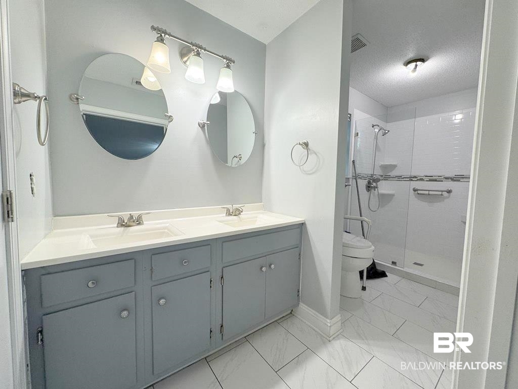 205 Montclair Loop Daphne, AL 36526 - Photo 10 of 19 Bathroom with toilet, an enclosed shower, a textured ceiling, and vanity