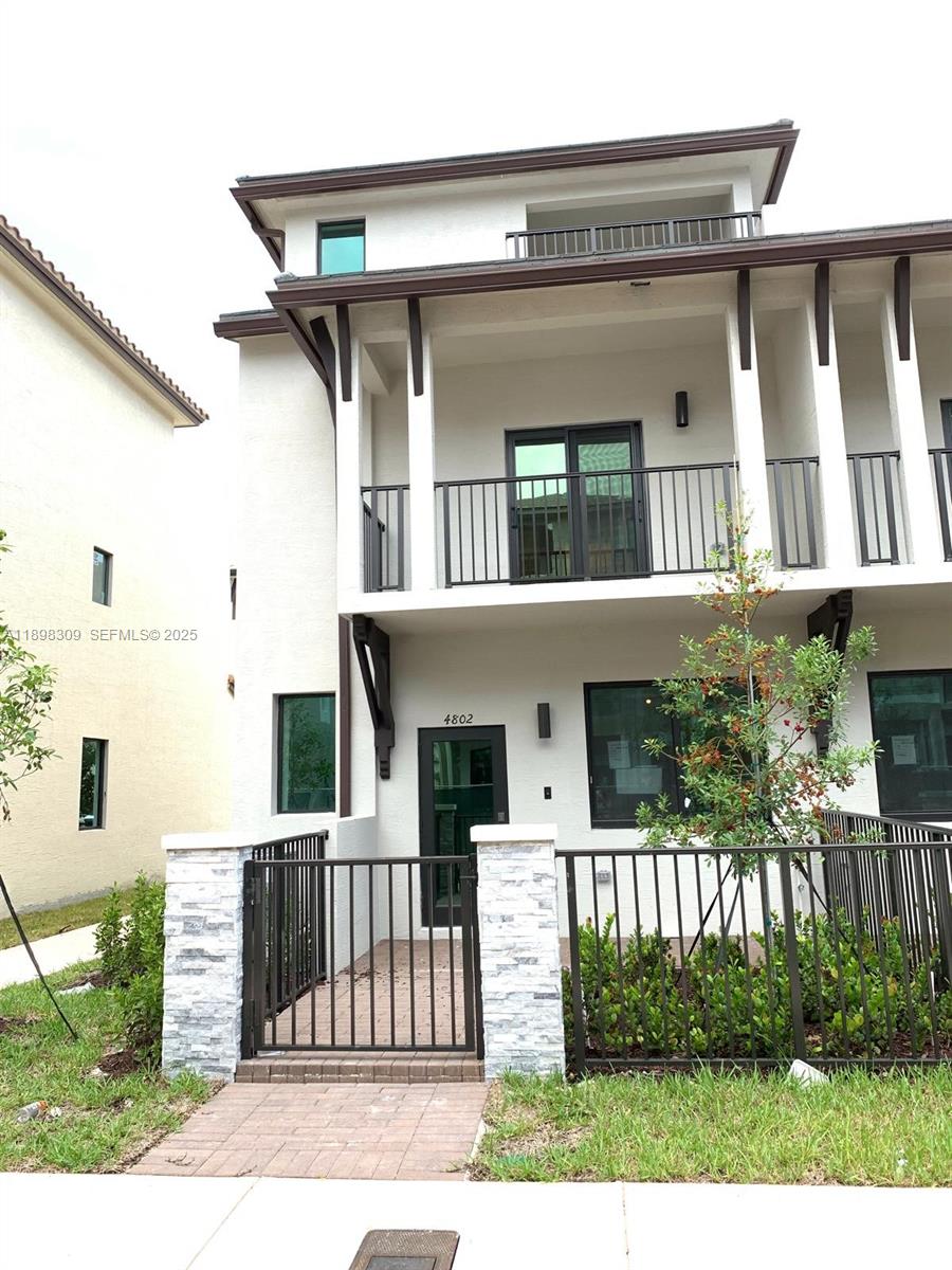4802 Northwest 83rd Path Doral, FL 33166 - Photo 2 of 25 a view of a white house with large windows and a small yard