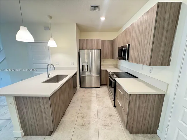 a kitchen with stainless steel appliances a refrigerator a sink a stove and oven