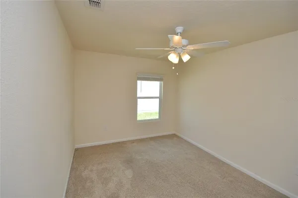 an empty room with a window and a fan