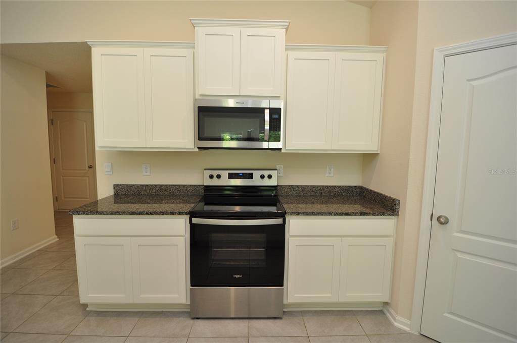 80 Oakleaf Way Palm Coast, FL 32137 - Photo 7 of 33 a kitchen with white cabinets and stainless steel appliances
