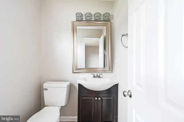 a bathroom with a toilet sink vanity and mirror