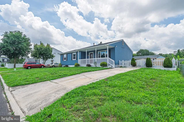 a view of house in front of a big yard with plants and large trees