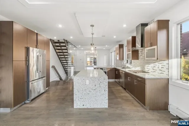 a large kitchen with kitchen island a large counter top space a sink stainless steel appliances and cabinets