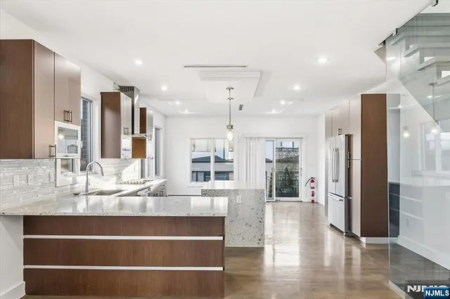 a view of kitchen with stainless steel appliances kitchen island granite countertop a refrigerator and cabinets