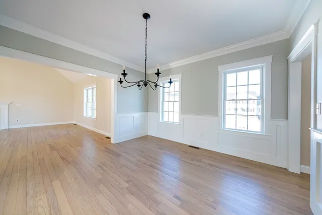 a view of an empty room with wooden floor ceiling fan and windows