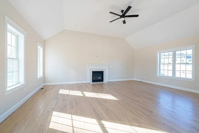 an empty room with wooden floor ceiling fan and windows