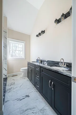 a spacious bathroom with a granite countertop sink a mirror and a bathtub