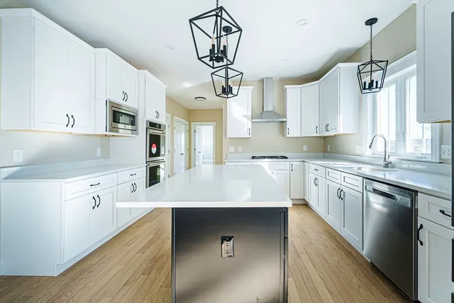 a kitchen with kitchen island granite countertop a sink a counter space appliances and cabinets