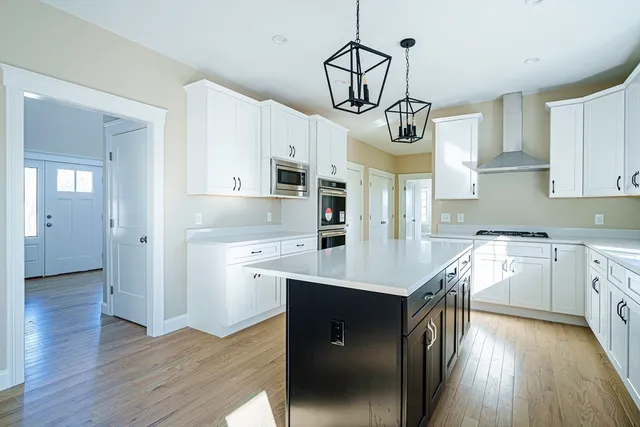 a kitchen with stainless steel appliances granite countertop a sink a stove a refrigerator and island with wooden floor